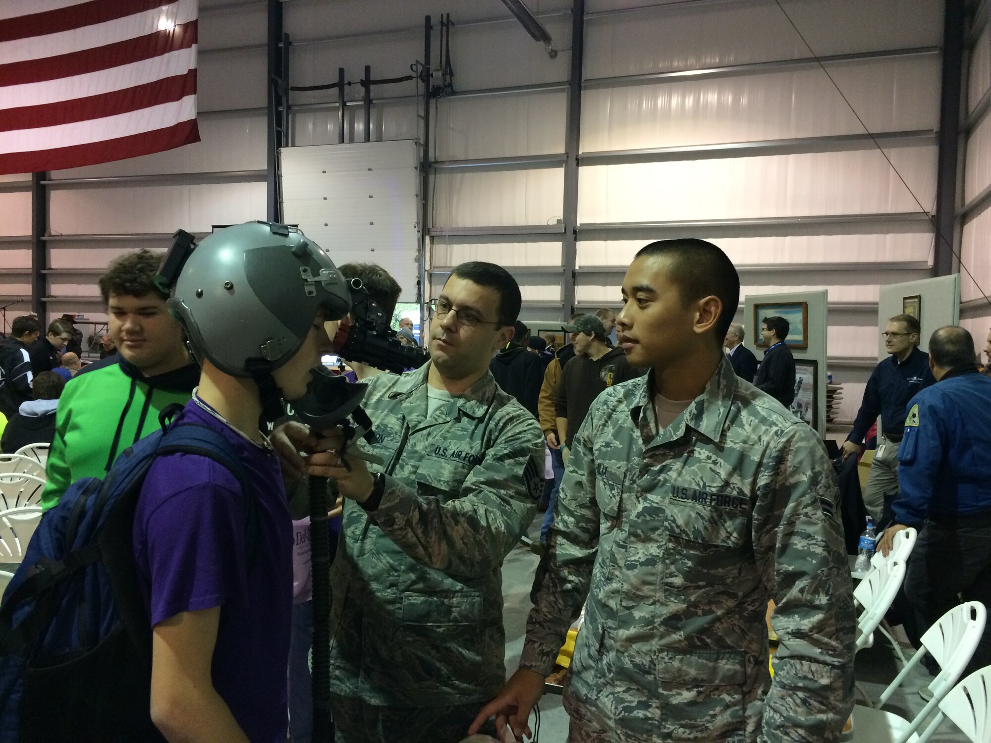 Staff Sgt. Jacob Johnson, 436th Operations Support Squadron, and Airman 1st Class Jeffrey Alix, 436th Operations Support Squadron, demonstrate the use of an aircrew flight helmet to a student at Wings and Wheels Aviation Education Day Oct. 2, 2015, in Georgetown, Del. Both Airmen are Air Force aircrew flight equipment technicians. (Courtesy photo)