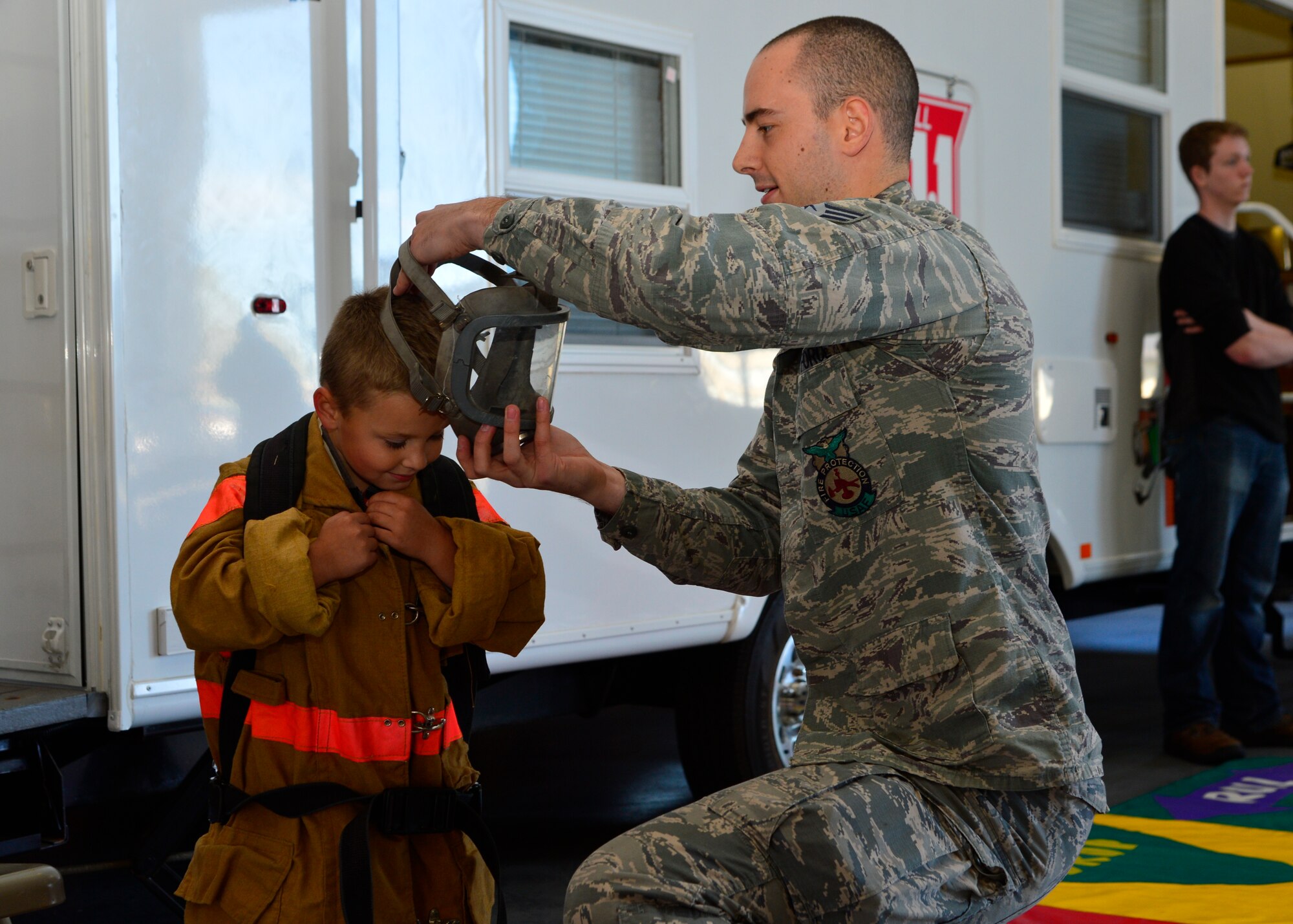 Senior Airman Scott Durham, 436th Civil Engineer Squadron firefighter, dresses Cyle Medeiros in bunker gear during the Fire Department Open House and Military Appreciation Day picnic Oct. 10, 2015, at Dover Air Force Base, Del. Various games and informational booths with prizes were set up for families to learn more about fire prevention tips and safety. (U.S. Air Force photo/Senior Airman William Johnson)