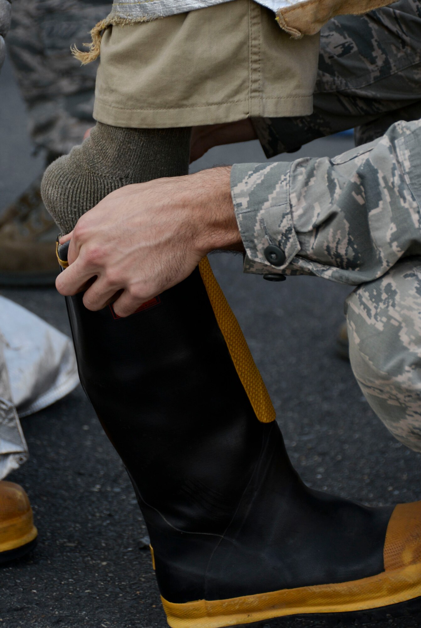 An Airman dons protective boots before competing in a fire muster for fire prevention week at Barksdale Air Force Base, La., Oct. 8, 2015. Each group of Airmen could choose to participate in the hotel pack, sled drag, Keiser Sled, dummy drag and hose pull. The obstacles allowed competitors to experience different skills firefighters require to fight fires safely and successfully. (U.S. Air Force photo/Senior Airman Amanda Morris)