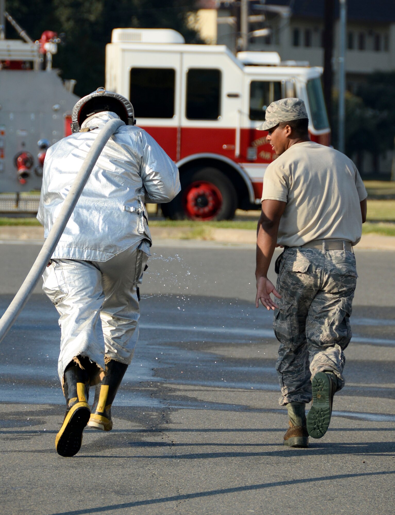 An Airman, left, rushes to the finish line during a fire muster competition at Barksdale Air Force Base, La., Oct. 8, 2015. Each group of Airmen could choose to participate in different obstacles to mimic firefighter duties. After reaching the finish line, the Airman charged the hose to signal that their team finished the course. (U.S. Air Force photo/Senior Airman Amanda Morris)