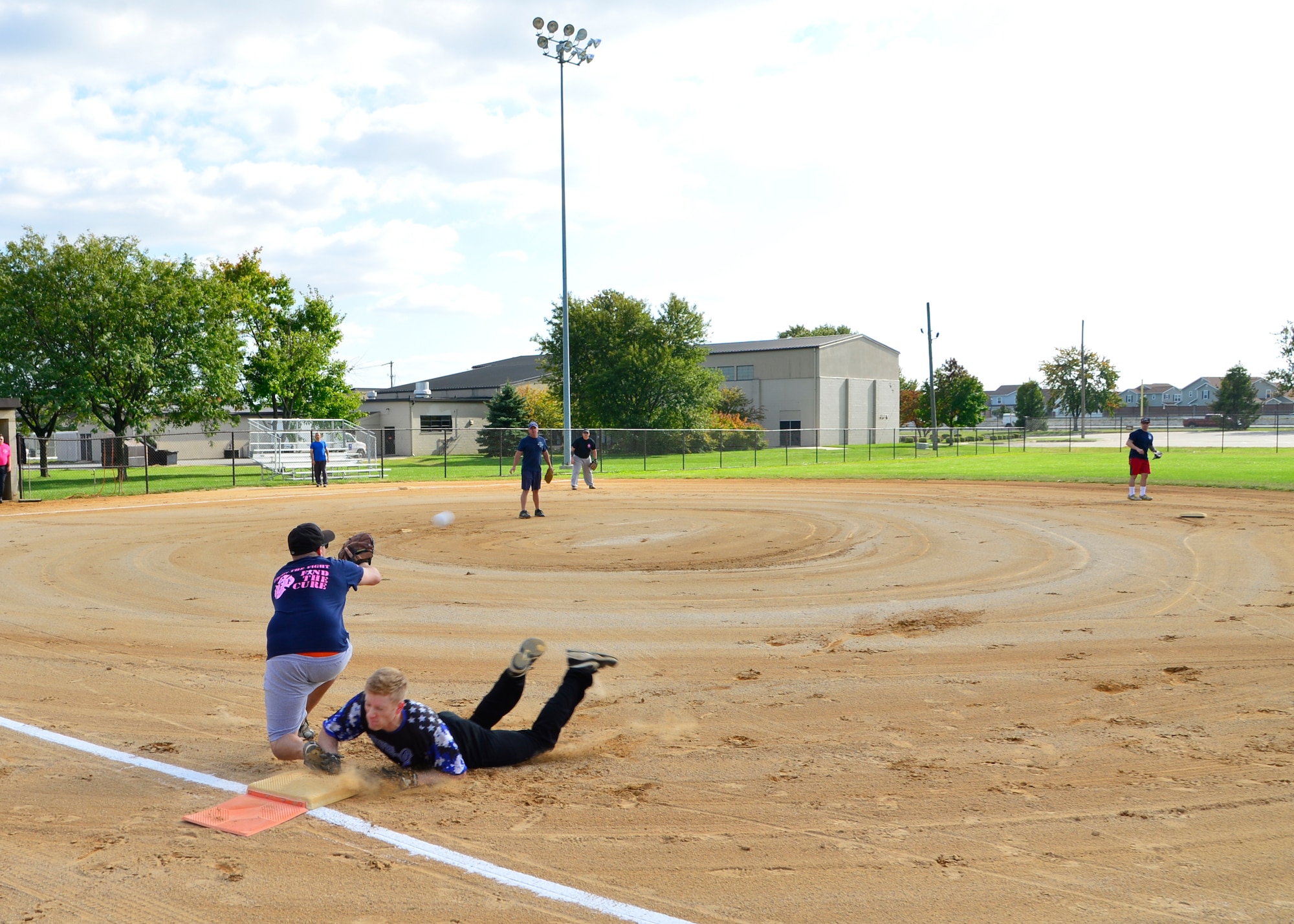 Jordan Hucks, 436th Security Forces Squadron left fielder, dives back to first base while Christopher Ladue, 436th Civil Engineer Squadron Fire Department, attempts to tag him out during the Battle of the Badges softball game Oct. 7, 2015, at the softball field on Dover Air Force Base, Del. The Battle of the Badges softball game is an annual event that brings cops and firefighters from Dover AFB together to participate in a game that strengthens a personal relationship between the two agencies. (U.S. Air Force photo/Senior Airman William Johnson)