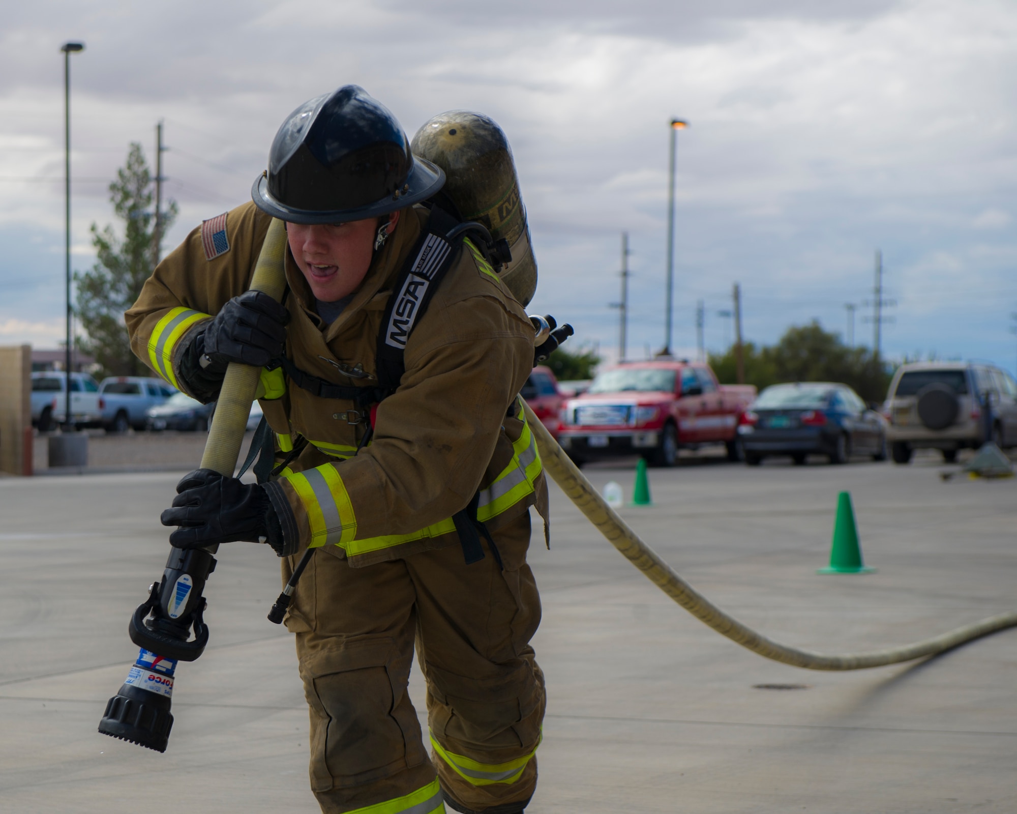 Senior Airman Michael Day, from 49th Civil Engineer Squadron fire protections, drags a fire hose across the finish line during the firefighter muster challenge at Holloman Air Force Base, N.M., Oct. 9, 2015. The firefighter muster challenge is designed to show teams what it takes to endure the physical challenges that firefighters face on a regular basis. (U.S. Air Force photo by Airman 1st Class Emily A. Kenney/Released)