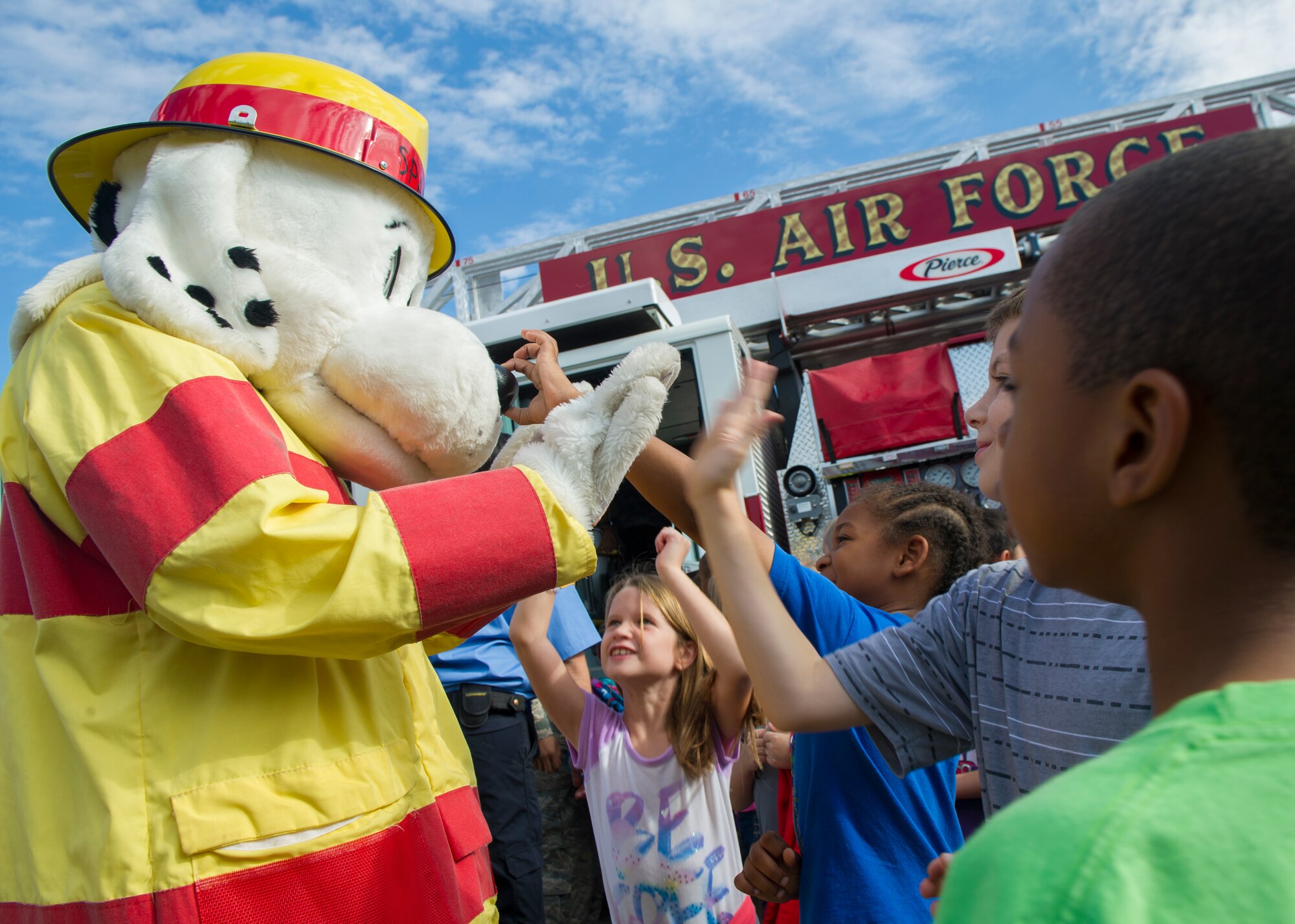 Sparky the Fire Dog high-fives kids during a visit at Holloman Elementary School, Oct. 6, 2015. During his visit, Sparky showed children different facets of the fire engine and taught the children about fire safety. Oct. 4 marked the beginning of Fire Prevention Week, which is observed annually to commemorate the great Chicago Fire of 1871. (U.S. Air Force photo by Airman 1st Class Emily A. Kenney/ Released)  
