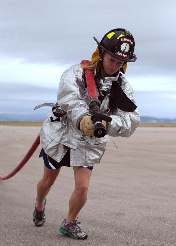 Second Lt. Laura Junge, 28th Force Support Squadron services flight officer in charge, performs a fire hose drag as a part of the annual Firefighter Challenge at Ellsworth Air Force Base, S.D., Oct. 2, 2015. The fire hose drag was the first of five obstacles in the event where teams competed for the fastest time. (U.S. Air Force photo by Airman Sadie Colbert/Released)