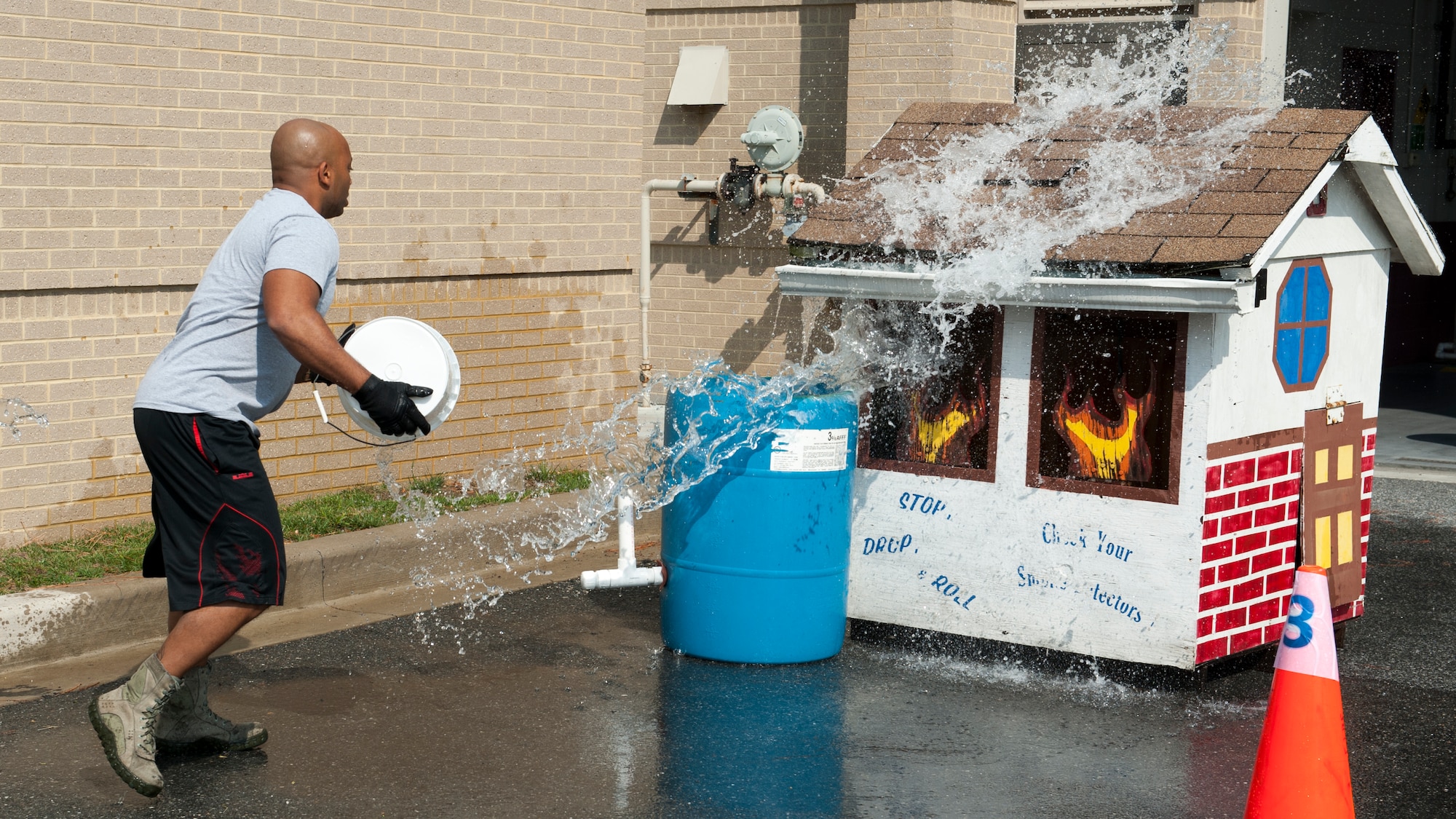 Master Sgt. Jamie Beard, 436th Security Forces Squadron first sergeant, throws a bucket of water onto a mock structure fire during the 2015 Fire Muster Oct. 8, 2015, at Dover Air Force Base, Del. The objective of this event was to throw as much water on the roof until enough water ran off to fill up the drum barrel. (U.S. Air Force photo/Senior Airman Zachary Cacicia)