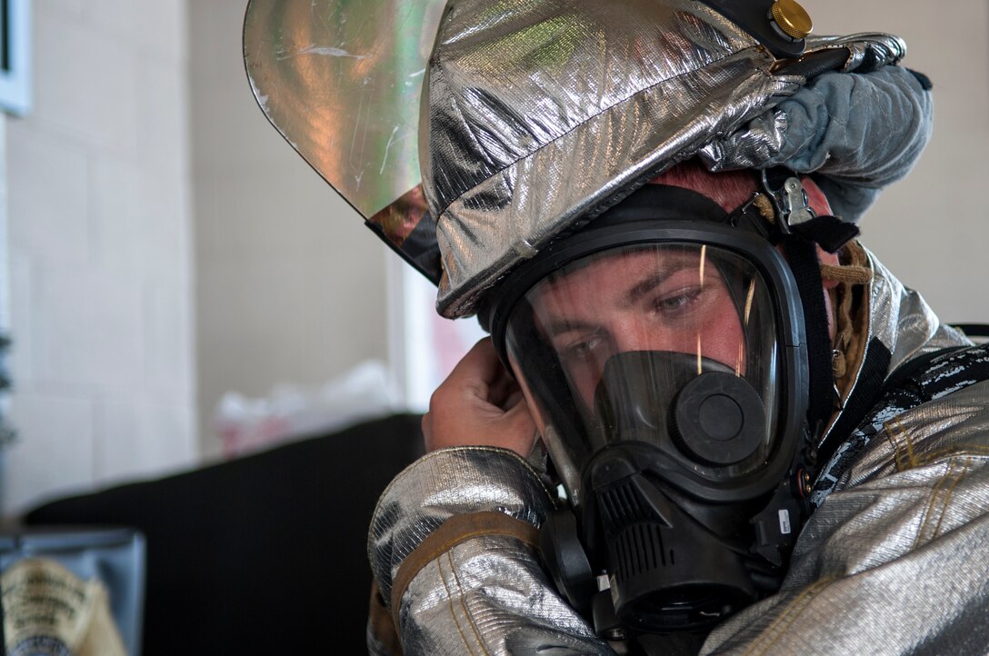 Airman Tom Krasinski, 4th Civil Engineer Squadron firefighter, puts on his oxygen mask, Sept. 17, 2015, at Seymour Johnson Air Force Base, North Carolina. The firefighters must don all protective equipment in less than two minutes after an alarm goes off before jumping into their assigned truck. (U.S. Air Force photo/Airman Shawna L. Keyes)