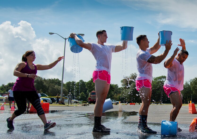 The “Pink Team” use coordination to pass back buckets filled with water during the Fire Muster Challenge Oct. 9 at Eglin Air Force Base, Fla.  Teams competed in the timed challenge that included shooting and rolling up the fire hose, hammer sled, victim-carry and water relay. The challenge closed out the base’s Fire Prevention Week activities.  (U.S. Air Force photo/Samuel King Jr.)