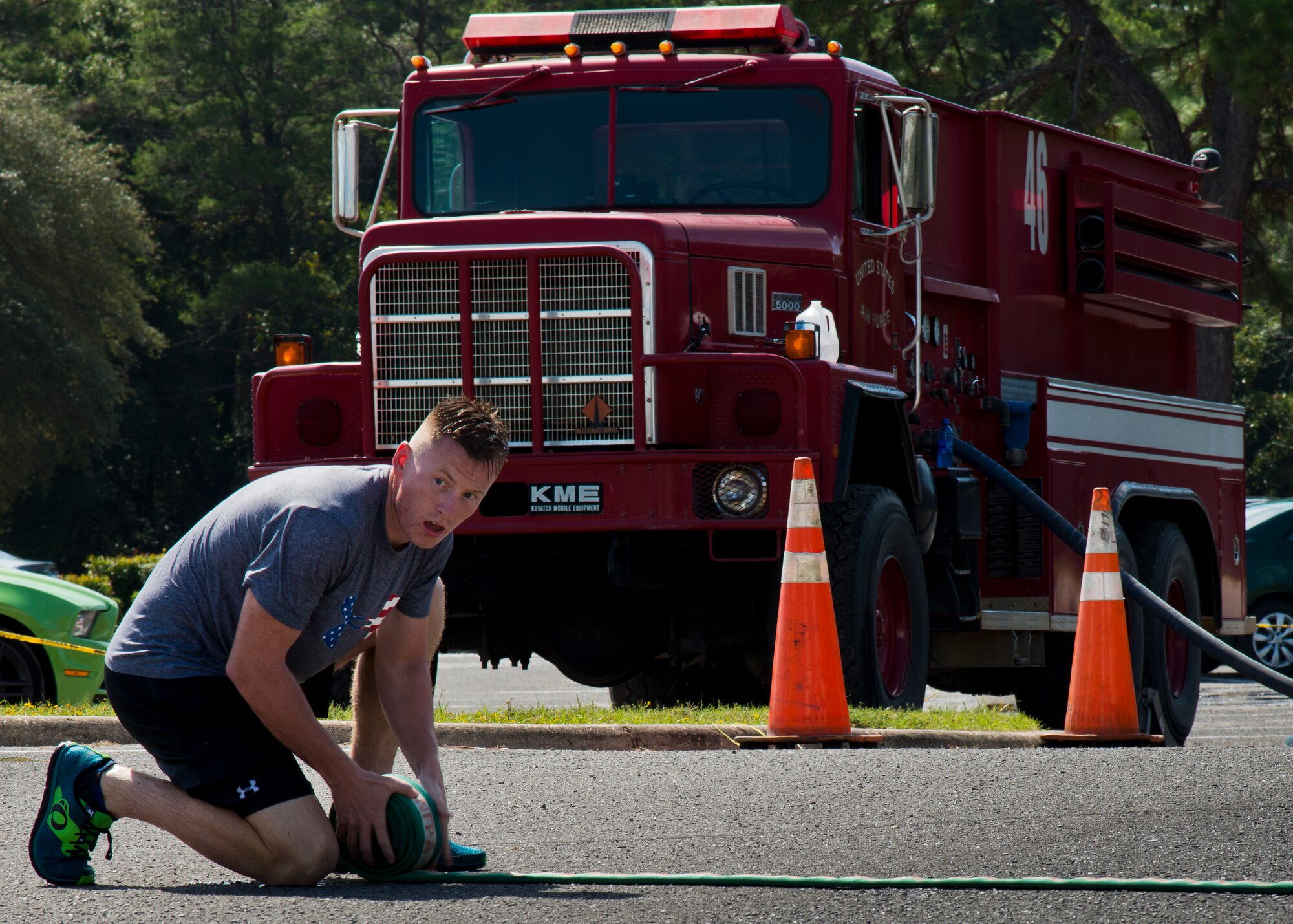 A participant checks on his teammates as he rolls up a fire hose during the Fire Muster Challenge Oct. 9 at Eglin Air Force Base, Fla.  Teams competed in the timed challenge that included shooting and rolling up the fire hose, hammer sled, victim-carry and water relay. The challenge closed out the base’s Fire Prevention Week activities.  (U.S. Air Force photo/Samuel King Jr.)
