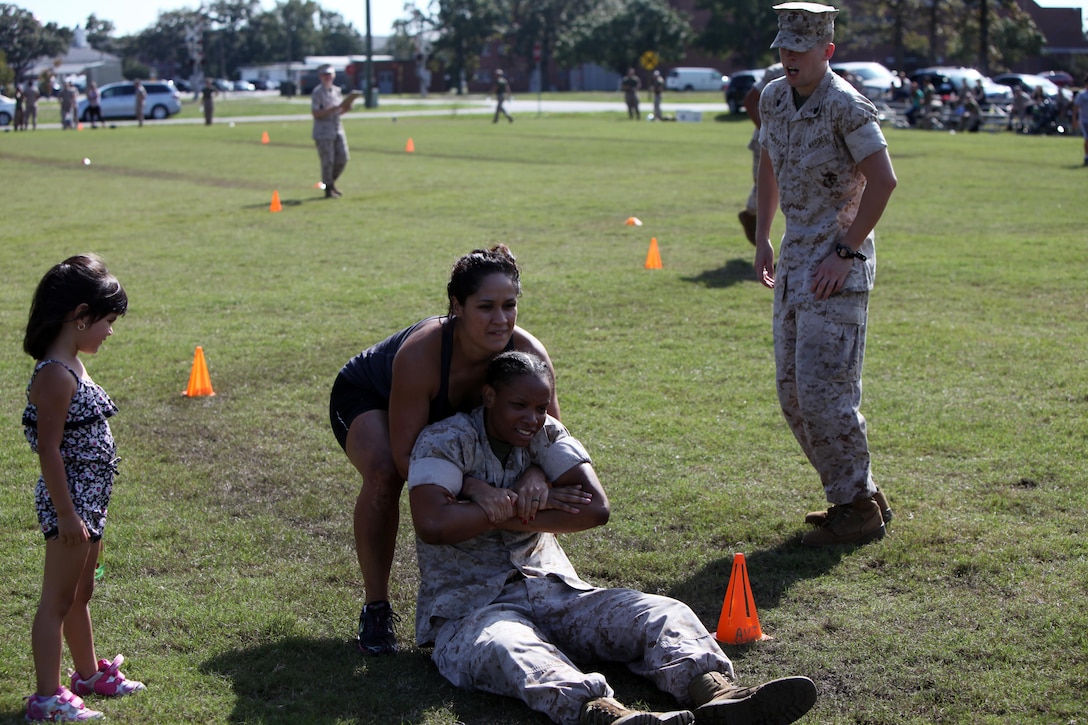 Vanessa Arreola lifts up Staff Sgt. Jessica Coit during the second annual Jayne and John Wayne Day hosted by Marine Aviation Logistics Squadron 14 at Marine Corps Air Station Cherry Point, N.C., Oct. 9, 2015. Family members toured their service member’s workspaces, participate in a portion of the Marines’ Combat Fitness Test and turned a few wrenches all to build relationships with the command, meet other families and build camaraderie with the unit. MALS-14 provides aviation logistics support, guidance, and direction to Marine Aircraft Group 14 squadrons including maintenance for aircraft and aeronautical components. Arreola is a spouse of Capt. Agustin Arreola, the MALS-14 operations officer. Coit is the substance abuse control officer with the squadron.