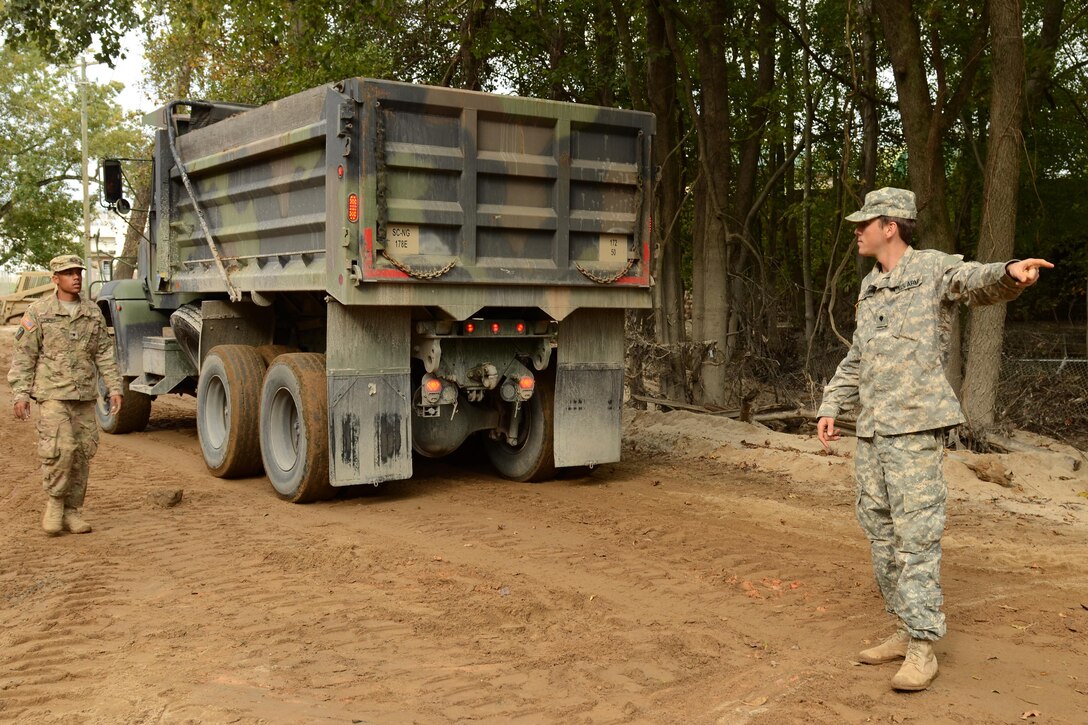 Army Spc. Austin Jones, right, directs a load of fill material with Army Spc. Dermaine Cherry to repair a section of Whitehouse Road affected by heavy rainfall in Columbia, S.C., Oct. 13, 2015. Jones and Cherry are engineers assigned to the South Carolina Army National Guard’s 1782nd Engineer Company. South Carolina Air National Guard photo by Senior Master Sgt. Edward Snyder