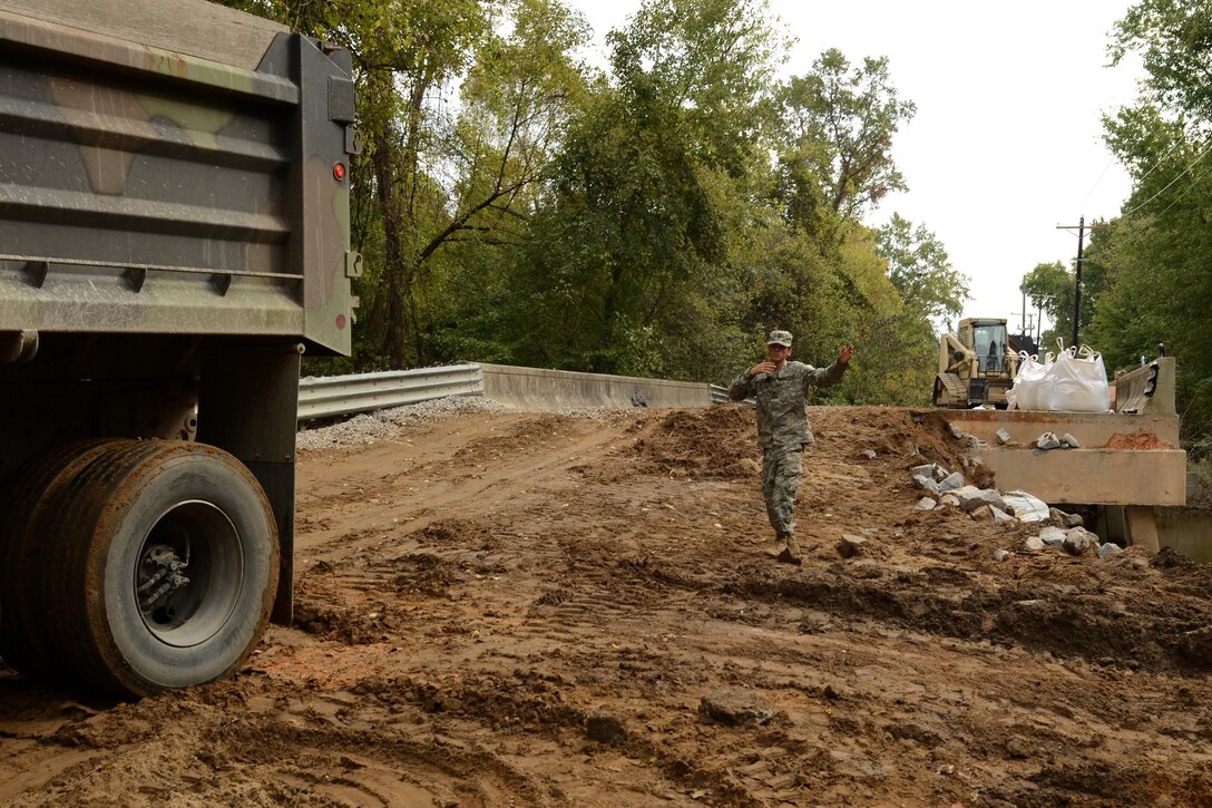 Army Spc. Austin Jones directs a load of fill material to repair a section of Whitehouse Road, near the Richland Wastewater Treatment Plant by heavy rainfall in Columbia, Oct. 13, 2015. Jones is an engineer assigned to the South Carolina Army National Guard’s 1782nd Engineer Company. South Carolina Air National Guard photo by Senior Master Sgt. Edward Snyder