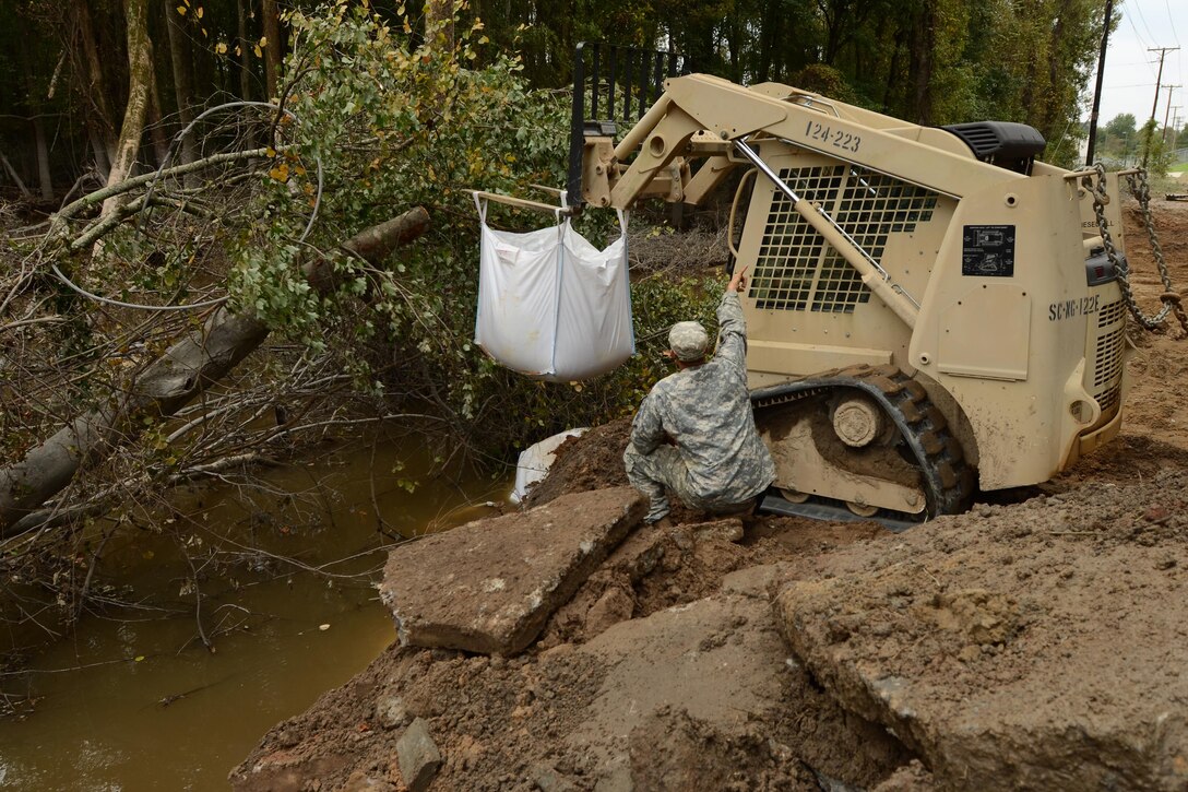 Army 1st Lt. Paul Bennett directs the placement of a 1,000 pound sandbag to repair a section of Whitehouse Road, near the Richland Wastewater Treatment Plant by heavy rainfall in Columbia, S.C., Oct. 13, 2015. Bennett is an engineer assigned to the South Carolina Army National Guard’s 1782nd Engineer Company. South Carolina Air National Guard photo by Senior Master Sgt. Edward Snyder