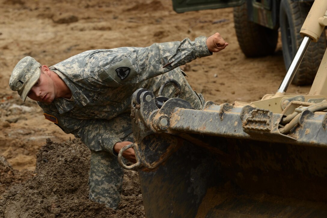 Army 1st Lt. Paul Bennett uses hand signals to direct a heavy equipment operator with fill-dirt placement while helping to repair a section of Whitehouse Road affected by heavy rainfall in Columbia, S.C., Oct. 13, 2015. Bennett is an engineer assigned to the South Carolina Army National Guard’s 1782nd Engineer Company. South Carolina National Guard photo by Air Force Senior Master Sgt. Edward Snyder
