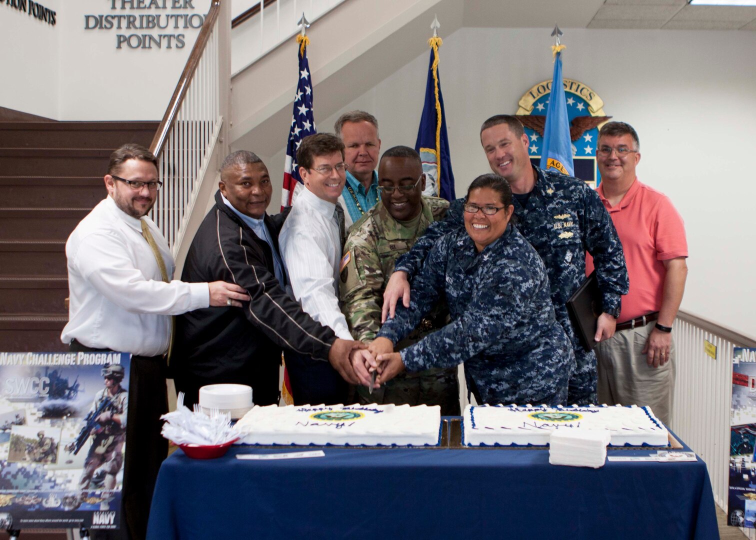 DLA Distribution commander Army Brig. Gen. Richard Dix, center, cuts a cake honoring the Navy’s 240th birthday alongside DLA Distribution’s active, reserve and retired Navy sailors. 