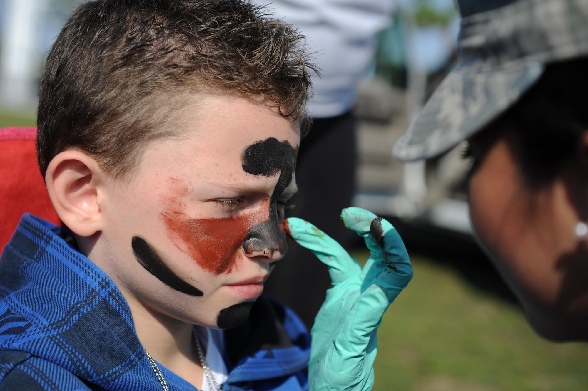Remington Eyer, son of Capt. Jarrett Eyer, 81st Surgical Operations Squadron general surgeon, has his face painted by Senior Airman Andrea Saavedra, 81st MSGS surgical technician, during Operation Hero Oct. 10, 2015, Keesler Air Force Base, Miss. The event was designed to help children better understand what happens when their parents deploy.  (U.S. Air Force photo by Kemberly Groue)