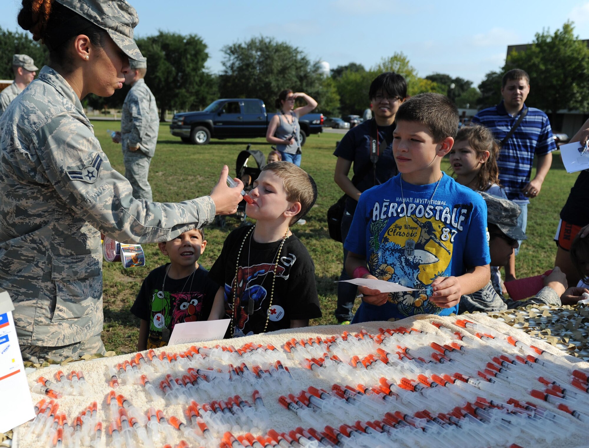 Airman 1st Class Jennifer Tatum, 81st Medical Operations Squadron medical technician, administers “a shot” in the form of juice to the children of Tech. Sgt. James Nottle, 338th Training Squadron instructor, during Operation Hero Oct. 10, 2015, Keesler Air Force Base, Miss. The event was designed to help children better understand what happens when their parents deploy.  (U.S. Air Force photo by Kemberly Groue)