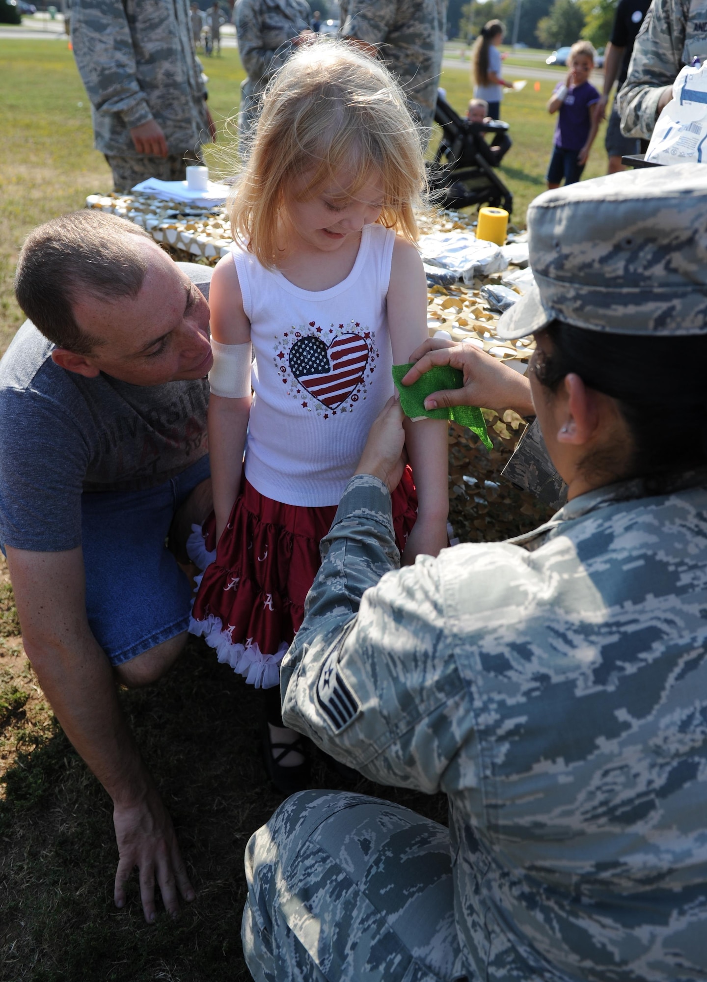 Staff Sgt. Ebony Santiago, 81st Medical Operations Squadron mental health NCO in charge, wraps a bandage around the arm of Chloe Ferguson, daughter of Tech. Sgt. Shaun Ferguson, 81st Security Forces Squadron unit deployment manager, during Operation Hero Oct. 10, 2015, Keesler Air Force Base, Miss. The event was designed to help children better understand what happens when their parents deploy.  (U.S. Air Force photo by Kemberly Groue)