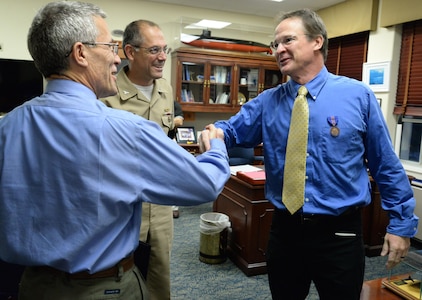 Naval Surface Warfare Center, Carderock Division (NSWCCD) Technical Director Dr. Joseph (Tim) Arcano (left) and NSWCCD Commanding Officer Capt. Richard Blank congratulate Alan Griffitts, director, NSWCCD Acoustic Research Detachment, Bayview, Idaho, on receiving the Meritorious Civilian Service Award at NSWCCD in West Bethesda, Md., Oct. 9, 2015. (U.S. Navy photo by Jay Pinsky/Released)