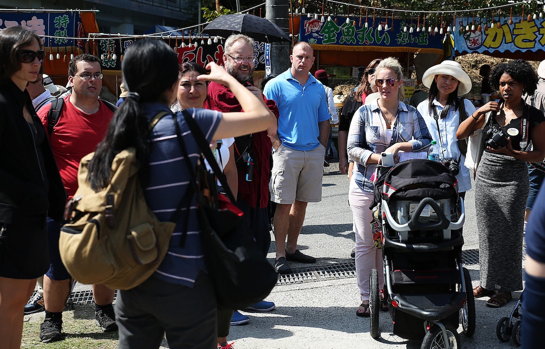 Mikie Watanabe, cultural adaption specialist with the cultural adaption program, speaks to Marine Corps Air Station Iwakuni, Japan, residents during a trip to the annual Japanese Calligraphy Brush Festival, in Kumano, Hiroshima Prefecture, Sept. 23, 2015. Guests wandered through the brush decorated city, where they interacted with Japanese locals, practiced their calligraphy skills and enjoyed local cuisine. The cultural adaption program aboard station coordinated this event to provide service members and their families a chance to travel beyond the installations gates and experience the Japanese culture.