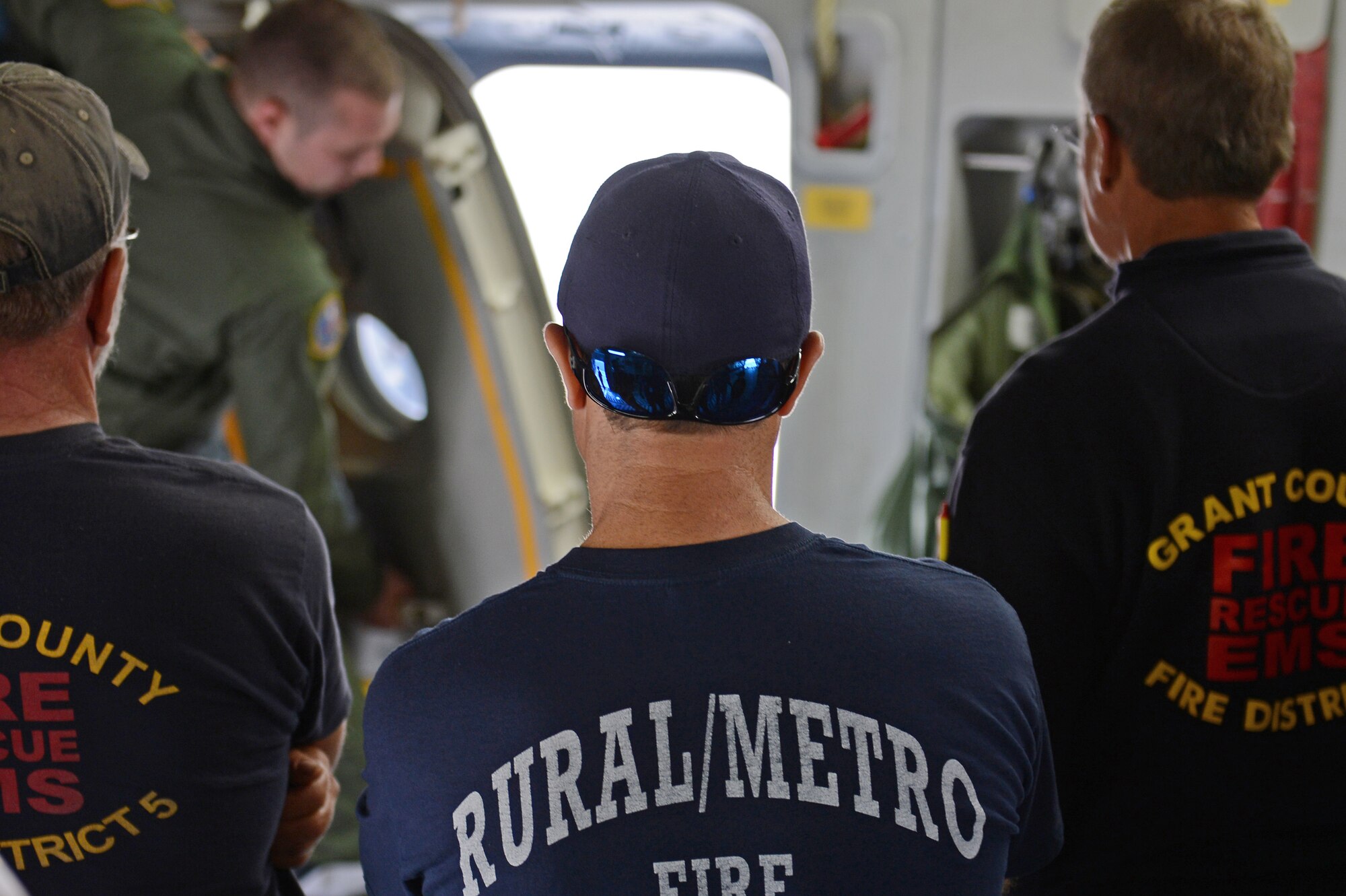 Staff Sgt. Mathew Vanourek (background), 728th Airlift Squadron loadmaster, shows members of the Grant County fire department how to open an exit door during a C-17 Globemaster III tour at Moses Lake, Wash., Oct. 9, 2015. The fire department received a tour of the aircraft as well as interacted with Airmen to better understand the aircraft and Team McChord’s mission. (U.S. Air Force photo/Senior Airman Divine Cox)