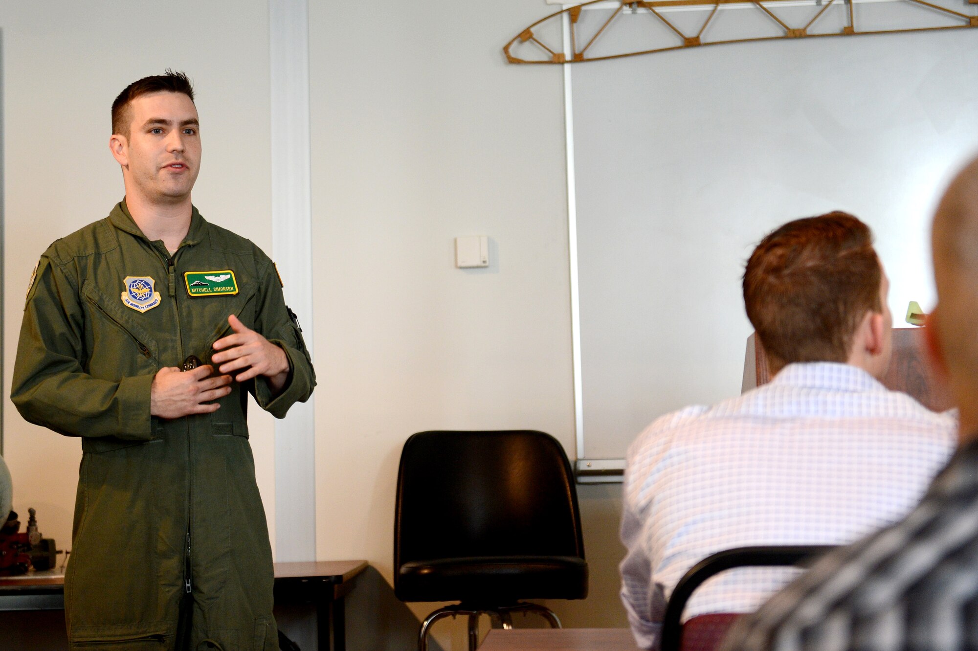 Capt. Mitchell Simonsen, 62nd Airlift Wing flight safety officer, briefs aviation students from Big Bend Community College about various missions and training routes during a C-17 Globemaster III tour at Moses Lake, Wash., Oct. 9, 2015. During the briefing, Simonsen stressed the importance of communication and how to avoid midair collisions. The students watch videos with bad examples of communication and discussed ways to prevent aircraft accidents. (U.S. Air Force photo/Senior Airman Divine Cox)