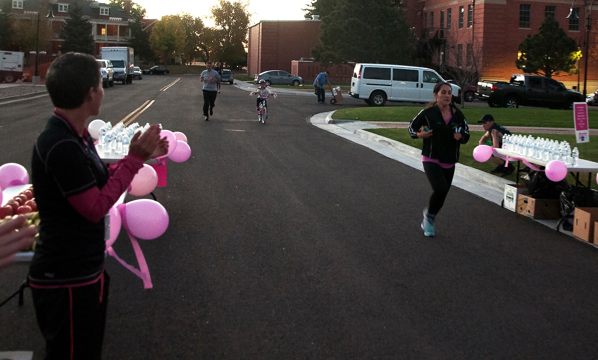 2nd Lt. Veronica Perez, 90th Missile Wing Public Affairs, runs through the finish line of a breast cancer awareness 2-kilometer run on F.E. Warren Air Force Base, Wyo., Oct. 14, 2015. Participants were given fresh fruit and water along with a bag of breast cancer awareness pamphlets upon reaching the finish line. (U.S. Air Force photo by Senior Airman Brandon Valle)