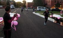 2nd Lt. Veronica Perez, 90th Missile Wing Public Affairs, runs through the finish line of a breast cancer awareness 2-kilometer run on F.E. Warren Air Force Base, Wyo., Oct. 14, 2015. Participants were given fresh fruit and water along with a bag of breast cancer awareness pamphlets upon reaching the finish line. (U.S. Air Force photo by Senior Airman Brandon Valle)