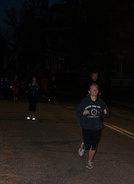 Airmen run down a street on F.E. Warren Air Force Base, Wyo., Oct. 14, 2015, during a 2-kilometer run to support breast cancer awareness. The early morning run helped raise awareness and support for those affected by breast cancer. (U.S. Air Force photo by Senior Airman Brandon Valle)