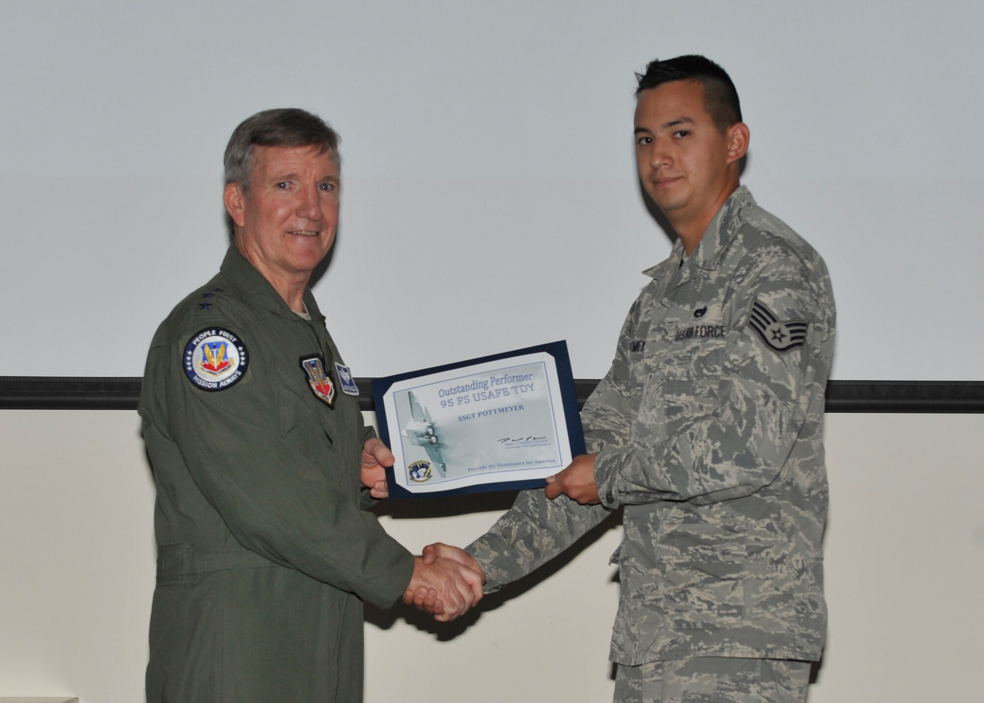 U.S. Air Force Gen. Hawk Carlisle, commander of Air Combat Command, presents a certificate for outstanding performance to Staff Sgt. Ryan Pottmeyer, 95th Aircraft Maintenance Unit dedicated crew chief, Oct. 6. Carlisle coined and presented certificates to 10 outstanding performers who excelled during the first ever Rapid Raptor to U.S. Air Forces in Europe training deployment. (U.S. Air Force photo by Airman 1st Class Sergio A. Gamboa/Released)