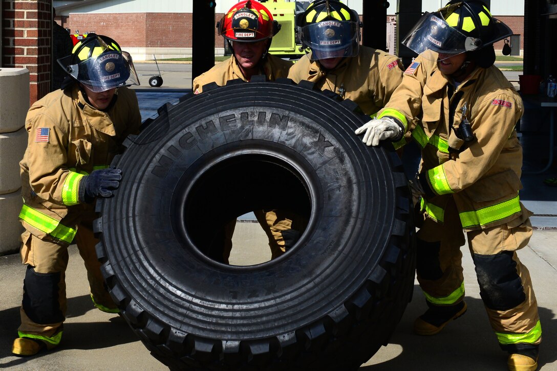 A group of U.S. Air Force Airmen flip a tire during the Firefighter Challenge at Langley Air Force Base, Va., Oct. 9, 2015. The tire flip was the last leg of the challenge and required the entire team to work together to complete. (U.S. Air Force photo by Airman 1st Class Derek Seifert/ Released)