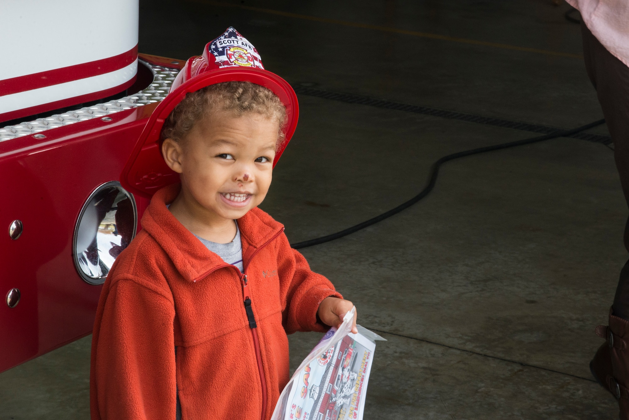 A child smiles for a photo with Sparky the Firehouse Dog, during fire prevention week, October 5, 2015, at the Patriots Landing Fire Station. Fire prevention week helps not only teaches children about preventing fires but also what steps to take in the event of a fire. (U.S. Air Force photo by Airman Gwendalyn Smith)