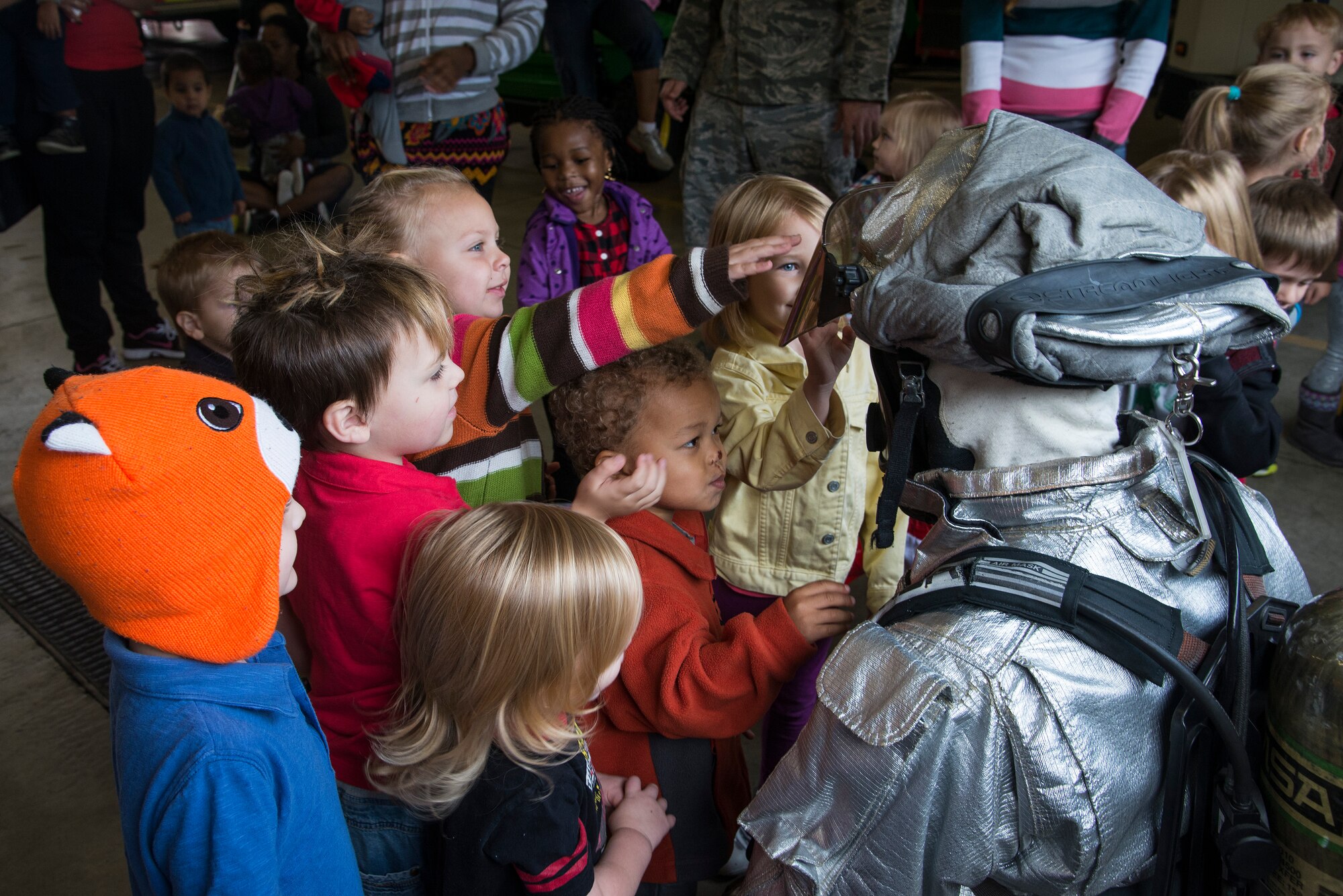Children look at the different parts of a fire suit, during fire prevention week, October 5, 2015, at the Patriots Landing Fire Station. Fire prevention week helps not only teaches children about preventing fires but also what steps to take in the event of a fire. (U.S. Air Force photo by Airman Gwendalyn Smith)