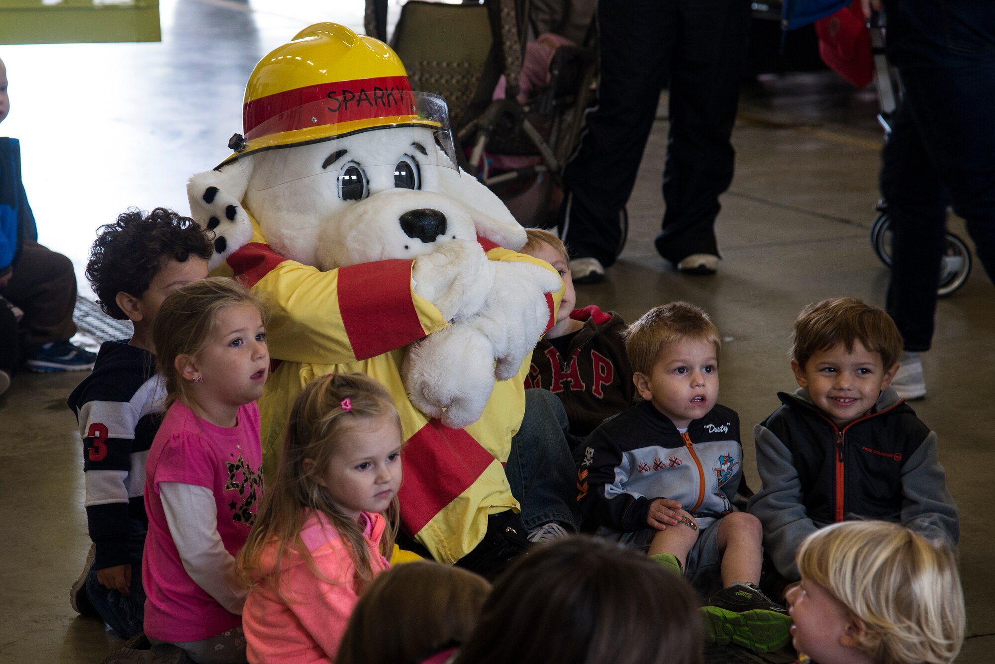Children watch a firefighter put on his suit with Sparky, the Firehouse Dog during fire prevention week, October 5, 2015, at the Patriots Landing Fire Station. Children learned how firefighters prepare for fires and the many safety precautions they take. (U.S. Air Force photo by Airman Gwendalyn Smith)