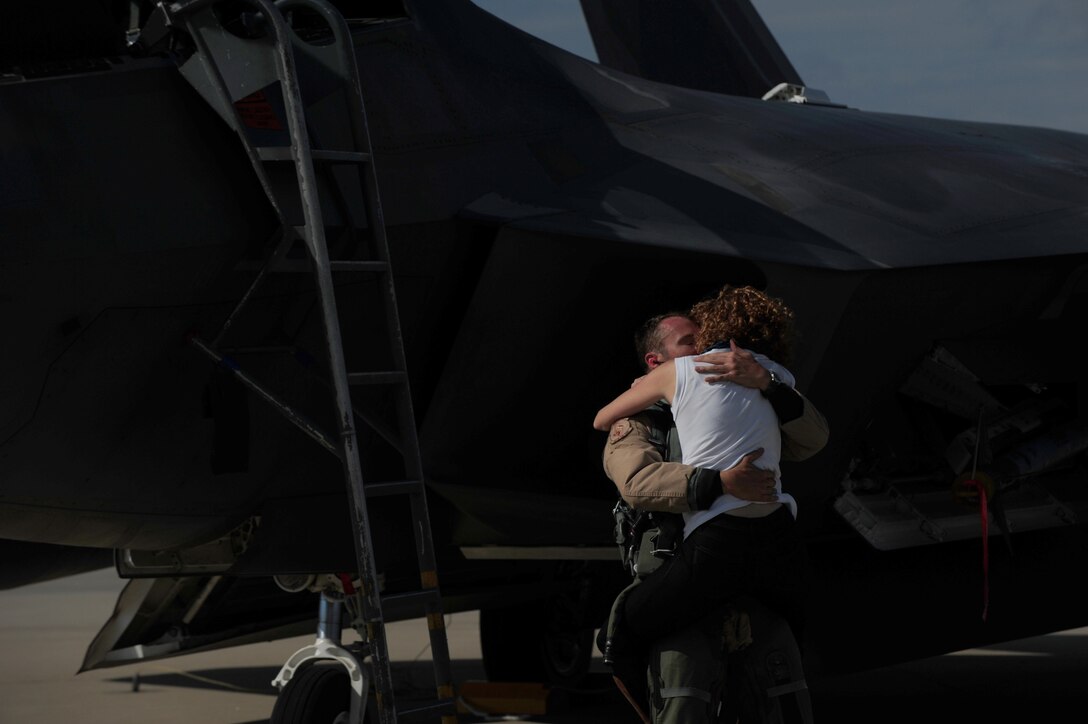 A U.S. Air Force Airman with the 1st Fighter Wing embraces his wife upon returning from a deployment to the Middle East at Langley Air Force Base, Va., Oct. 9, 2015.  Family and friends gathered on the flightline to greet the pilots returning from supporting operations in Iraq and Syria. (U.S. Air Force photo by Staff Sgt. Natasha Stannard/Released)