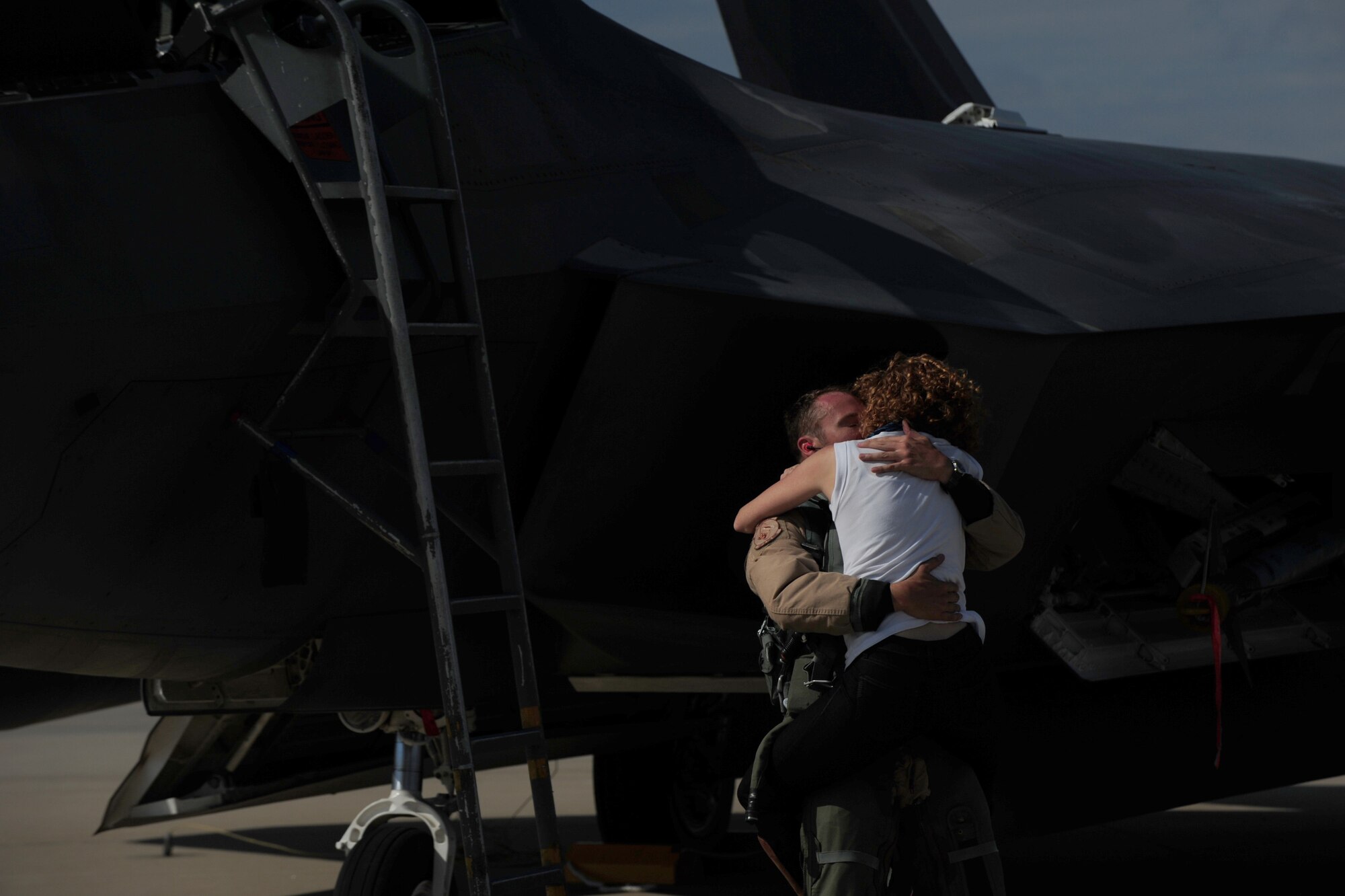 A U.S. Air Force Airman with the 1st Fighter Wing embraces his wife upon returning from a deployment to the Middle East at Langley Air Force Base, Va., Oct. 9, 2015.  Family and friends gathered on the flightline to greet the pilots returning from supporting operations in Iraq and Syria. (U.S. Air Force photo by Staff Sgt. Natasha Stannard/Released)