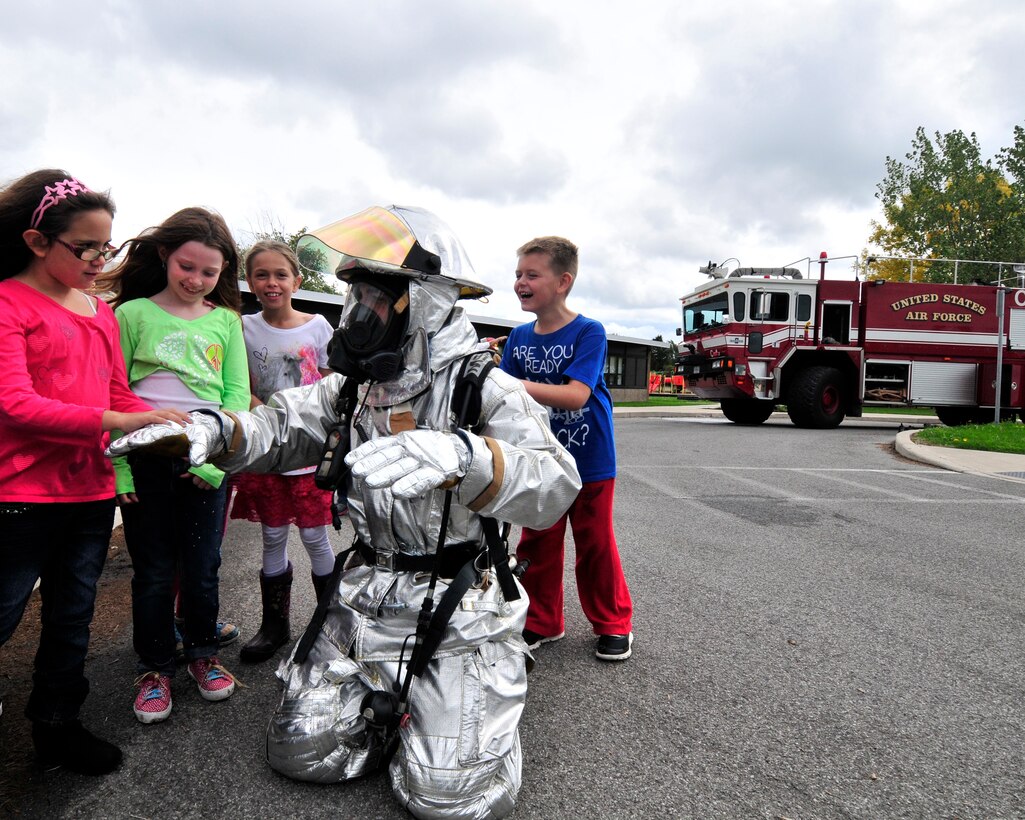 Fire Inspector Joseph Honsberger from the Niagara Falls Air Reserve Station Fire Department shows off a fire reflective suit to a group of children at the Pioneer Village School, Niagara Falls, N.Y. on October 9, 2015. Firefighters from the base were on hand to demonstrate and speak to children about fire safety during the national Fire Prevention Week. (U.S. Air Force photo by Peter Borys)