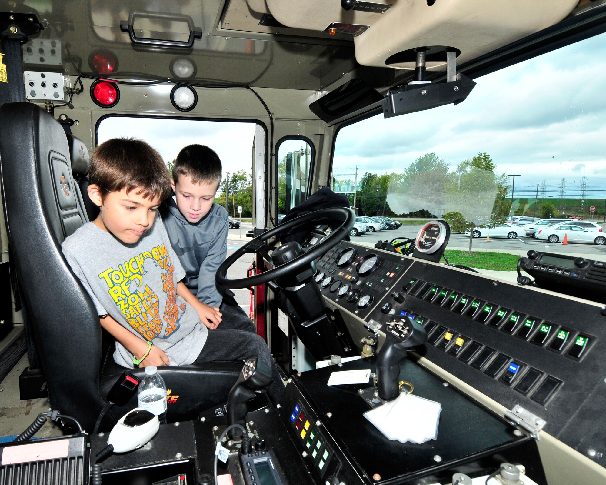 XX and XX check out the “Cool” buttons and switches inside the cab of a crash rescue truck from the Niagara Falls Air Reserve Station Fire Department at the Pioneer Village School, Niagara Falls, N.Y. on October 9, 2015.Firefighters from the base were on hand to demonstrate and speak to children about fire safety during the national Fire Prevention Week. (U.S. Air Force photo by Peter Borys)