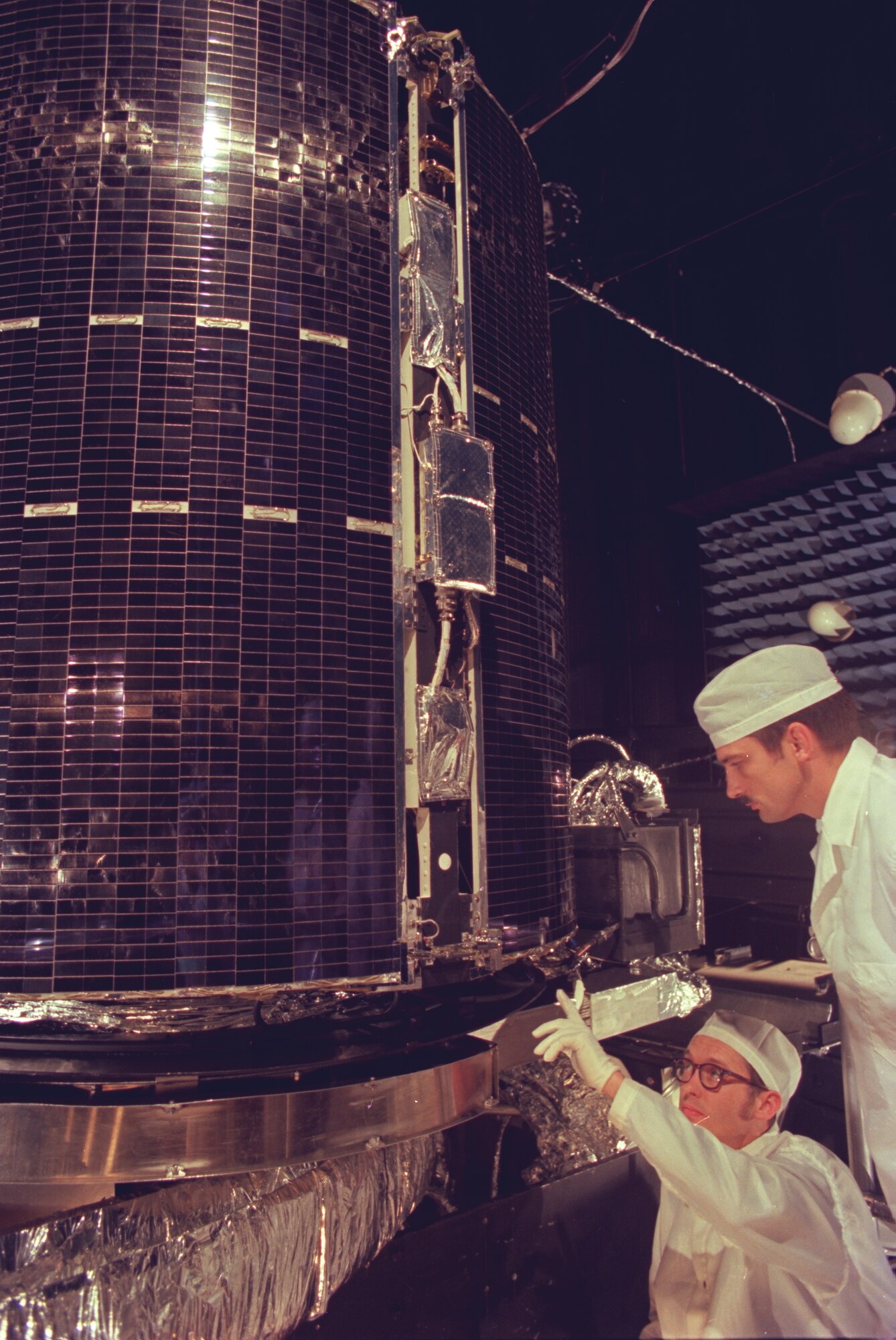 Initial testing of the NAVSTAR Global Positioning System (GPS) was conducted in the Mark 1 Space Chamber at AEDC during the late 1970s. Pictured here are AEDC personnel taking a close look at the stowed solar array panels that provide electricity for the NAVSTAR GPS satellite.  