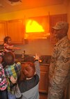 Children from the Grand Forks Air Force Base Youth Center hold and spray a fire hose while a member of the 319th Civil Engineer Squadron fire department helps guide them during a fire prevention activity Oct. 7, 2015, on Grand Forks AFB, North Dakota. The fire department, hosted multiple fire prevention events to emphasize the importance of fire safety. (U.S. Air Force photo by Senior Airman Xavier Navarro/Released) 