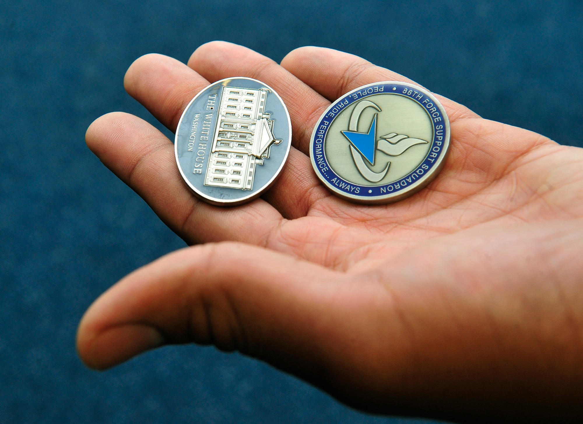 Sean Tatum, 86th Force Support Squadron caregiver, holds two coins he was awarded during a Red Cross Lifesaver Award ceremony Oct. 8, 2015, at Ramstein Air Base, Germany. Tatum was presented a White House challenge coin as well as his unit’s coin for the skills he used to stop a child from choking. (U.S. Air Force photo/Airman 1st Class Larissa Greatwood)