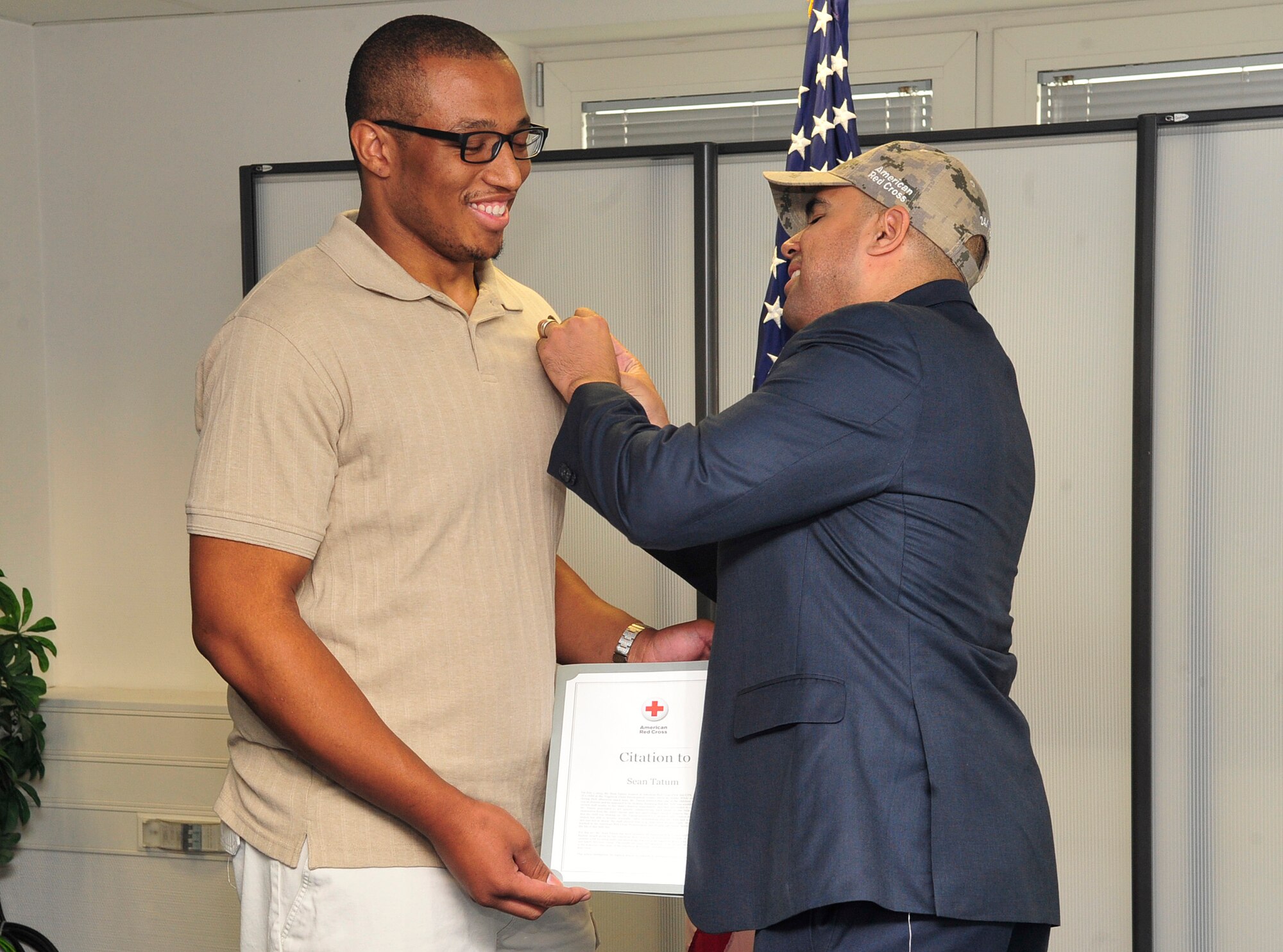 Sean Tatum, 86th Force Support Squadron caregiver, receives the Red Cross Lifesaver Award from Koby Langley, senior vice president of Service to the Armed Forces, during an award ceremony Oct. 8, 2015, at Ramstein Air Base, Germany. The Red Cross Lifesaver Award is a prestigious award given to recognize a lifesaving act performed by an individual who utilized skills learned through Red Cross health and safety training. (U.S. Air Force photo/Airman 1st Class Larissa Greatwood)