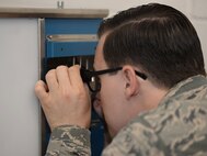 U.S. Air Force Staff Sgt. Anthony Sweat, 100th Maintenance Squadron nondestructive inspection journeyman, uses a specialized optical lens Sept. 2, 2015, on RAF Mildenhall, England. Using these lens means he’s able to measure and pinpoint specific discontinuities on radiographic film for weld certifications. (U.S. Air Force photo by Gina Randall/Released)