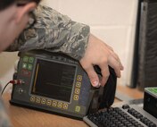 U.S. Air Force Staff Sgt. Anthony Sweat, 100th Maintenance Squadron nondestructive inspection journeyman, uses an ultrasonic test unit to perform an inspection Sept. 2, 2015, on RAF Mildenhall, England. The machine is able to transmit sound through a transducer into a test part where it’s analyzed on the screen to determine if any underlying defects exist. (U.S. Air Force photo by Gina Randall/Released)