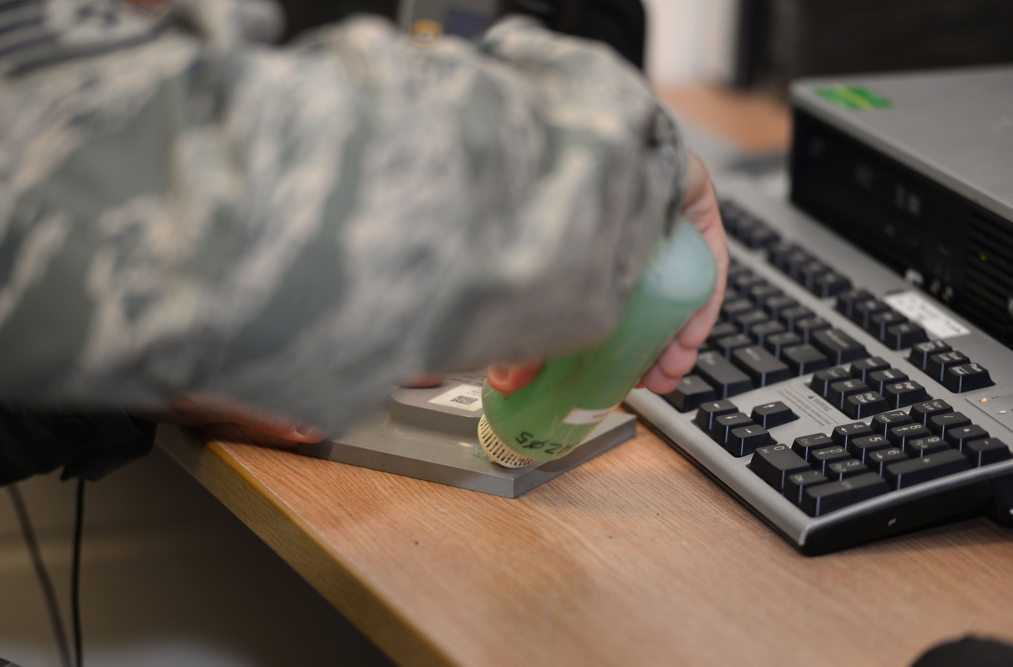 U.S. Air Force Staff Sgt. Anthony Sweat, 100th Maintenance Squadron nondestructive inspection journeyman, uses an ultrasonic couplant on an inspection standard for an inspection Sept. 2, 2015, on RAF Mildenhall, England. The inspection requires a liquid medium so sound can be transmitted into the part without interference. (U.S. Air Force photo by Gina Randall/Released)