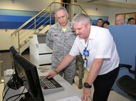 Mark Whatmough, right, 727th Air Mobility Squadron passenger services agent and Ministry of Defence employee, explains to U.S. Air Force Maj. Gen. Frederick H. Martin, U.S. Air Force Expeditionary Center commander, how the X-ray machine works in the passenger terminal during a visit Oct. 9, 2015, on RAF Mildenhall, England. Martin toured the passenger terminal, freight services and fleet services facilities, spoke with MoD civilians and military members about what they do, and held a question-and-answer session. (U.S. Air Force photo by Karen Abeyasekere/Released)