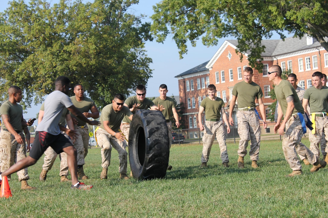 Marines roll a tire through the Zombie Gauntlet at the CFC kick-off field meet. The Marines wearing ribbons around their waists have not yet been turned into zombies.