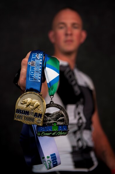Staff Sgt. Josh Hull, NCO in charge of the Minot Air Force Base Honor Guard, holds his Iron Man Challenge medals at Minot AFB, N.D., Oct. 13, 2015. After training nine months for his first Iron Man Challenge, it was cancelled at the last minute, which inspired him to run two more. (U.S. Air Force photo/Airman 1st Class Christian Sullivan)
