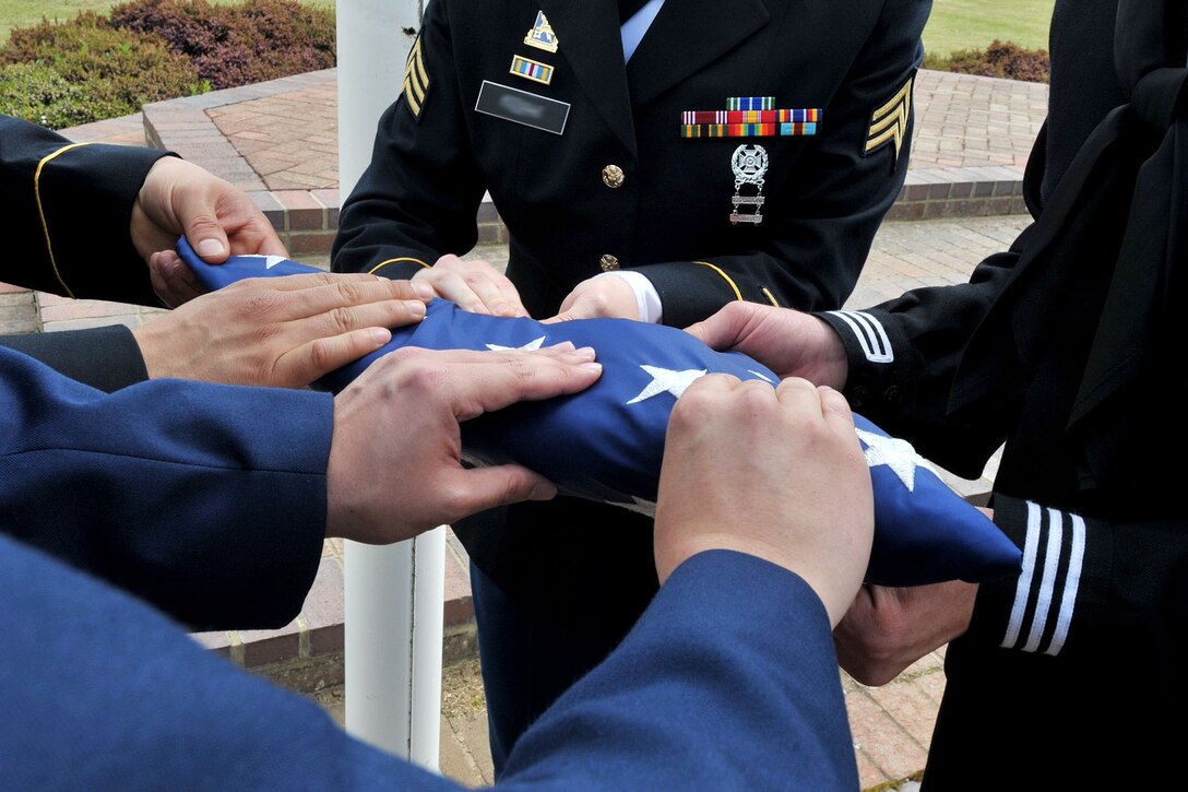 U.S. Service members with the RAF Molesworth Joint Honor Guard fold the American flag during a retreat ceremony at RAF Molesworth, United Kingdom, June 5, 2015. As the only American joint honor guard in the United Kingdom, the newly-reconstructed honor guard performs ceremonies spanning all of England, and parts of Ireland and Germany. (The last names of personnel have been blurred for security purposes)(U.S. Air Force photo by Staff Sgt. Ashley Hawkins/Released)