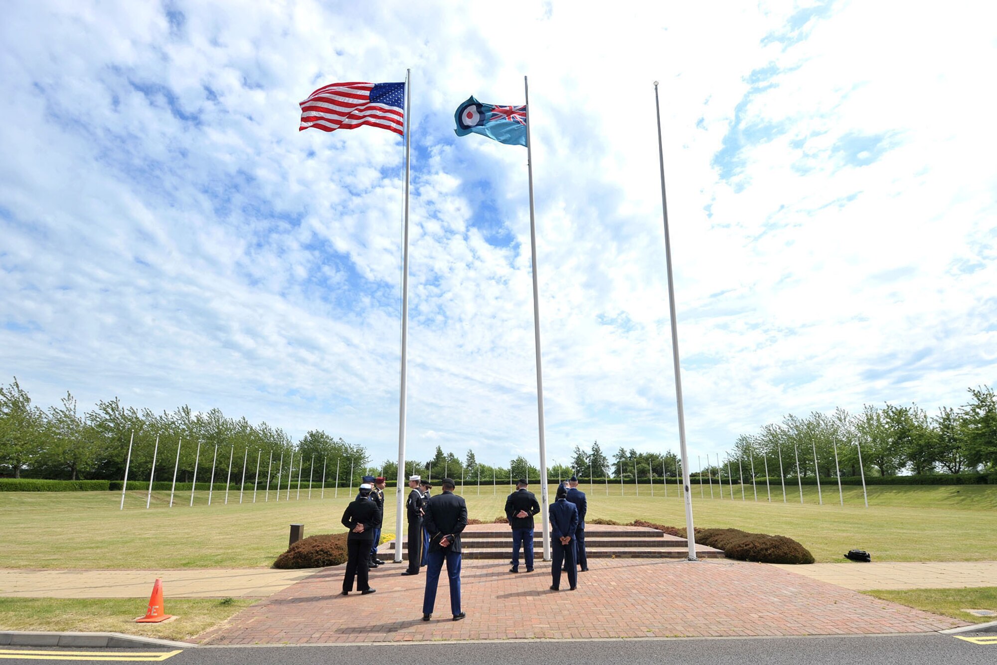 U.S. Service members with the RAF Molesworth Joint Honor Guard stand at parade rest before lowering the American and RAF Ensign flags, during a retreat ceremony at RAF Molesworth, United Kingdom, June 5, 2015. The newly-reconstructed honor guard team consists of U.S. Army, Marine Corps, Navy and Air Force personnel who showcase the American flag throughout England and other countries, such as Germany. (U.S. Air Force photo by Staff Sgt. Ashley Hawkins/Released)