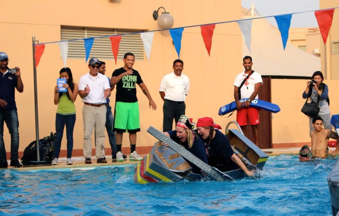 Megan Crimmins (front) and Nicole Chewning work to keep their boat from capsizing as they race to the finish during the Naval Support Activity Bahrain 240th Navy Birthday Cardboard Regatta Oct. 8. 